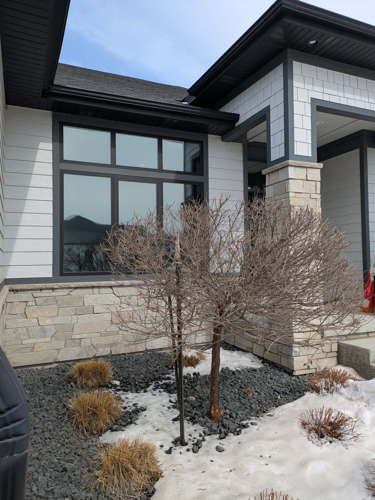 Tall black-framed windows on the front of a home in Dakota Dunes with window film installed