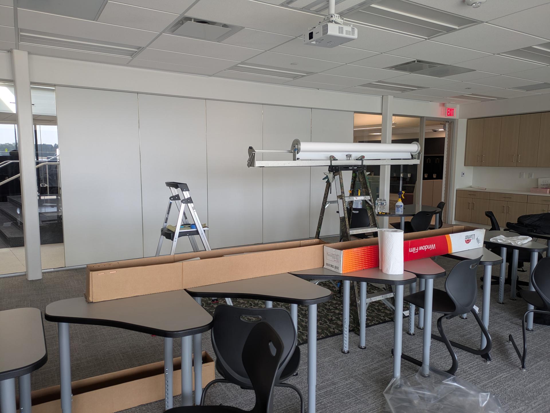 Open office with glass partitions and a ladder during window film installation